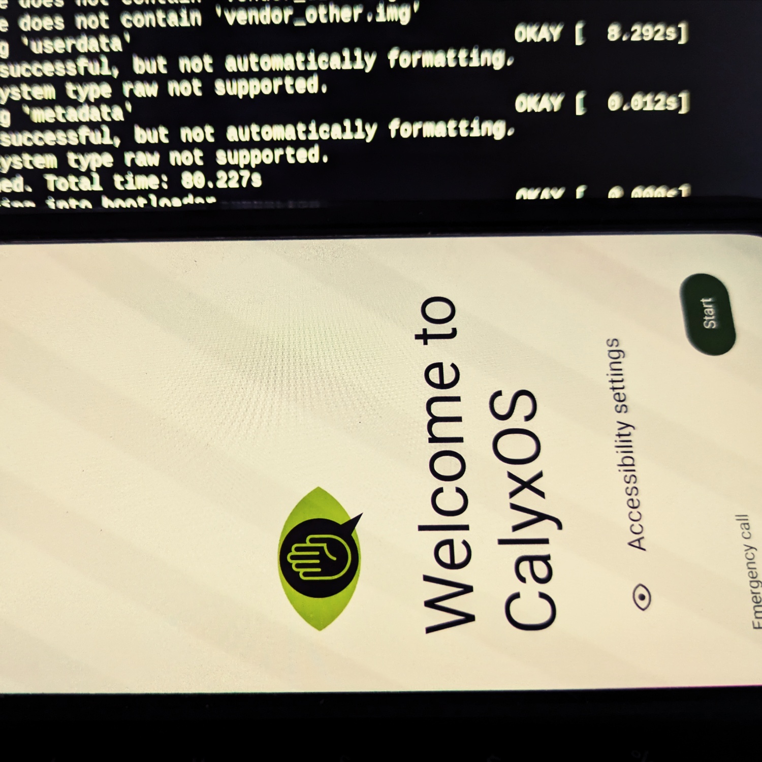 Ein Smartphone mit dem Startbildschirm von CalyxOS, im Hintergrund ein Linux-Terminal