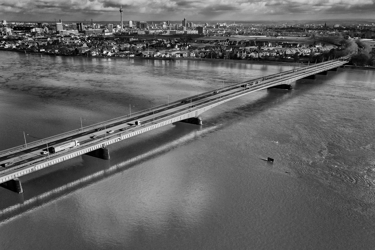 Eine Autobahnbrücke bei Hochwasser. Drohnenaufnahme in Schwarzweiß.
