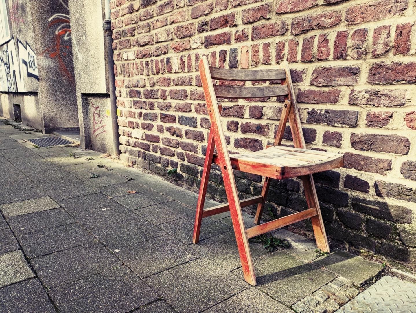 An old wooden chair left outside on a sidewalk.