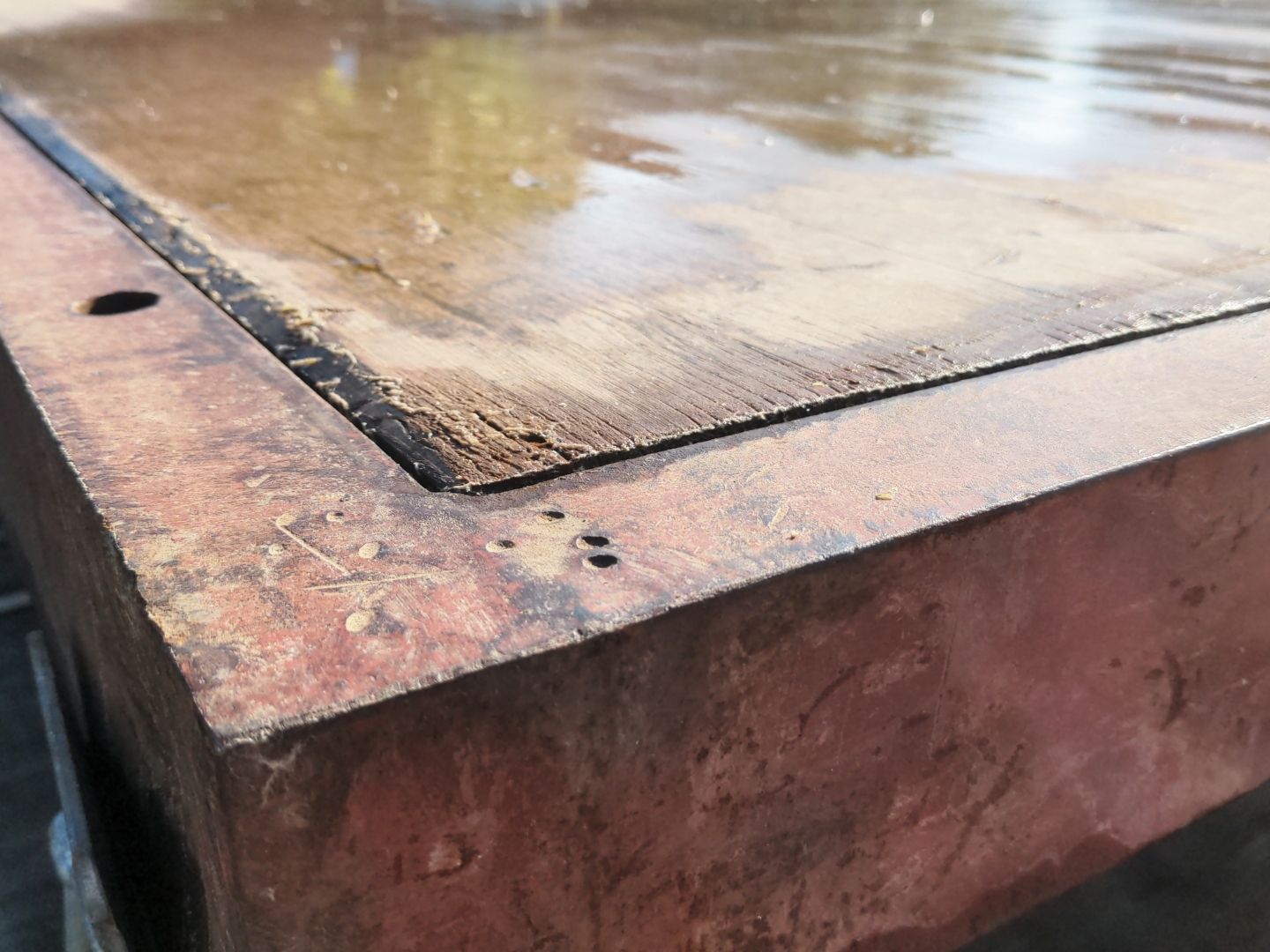 Ecke der Bodenplatte eines Festzeltes. Rahmen aus rostigem Metall, Boden aus Holz.