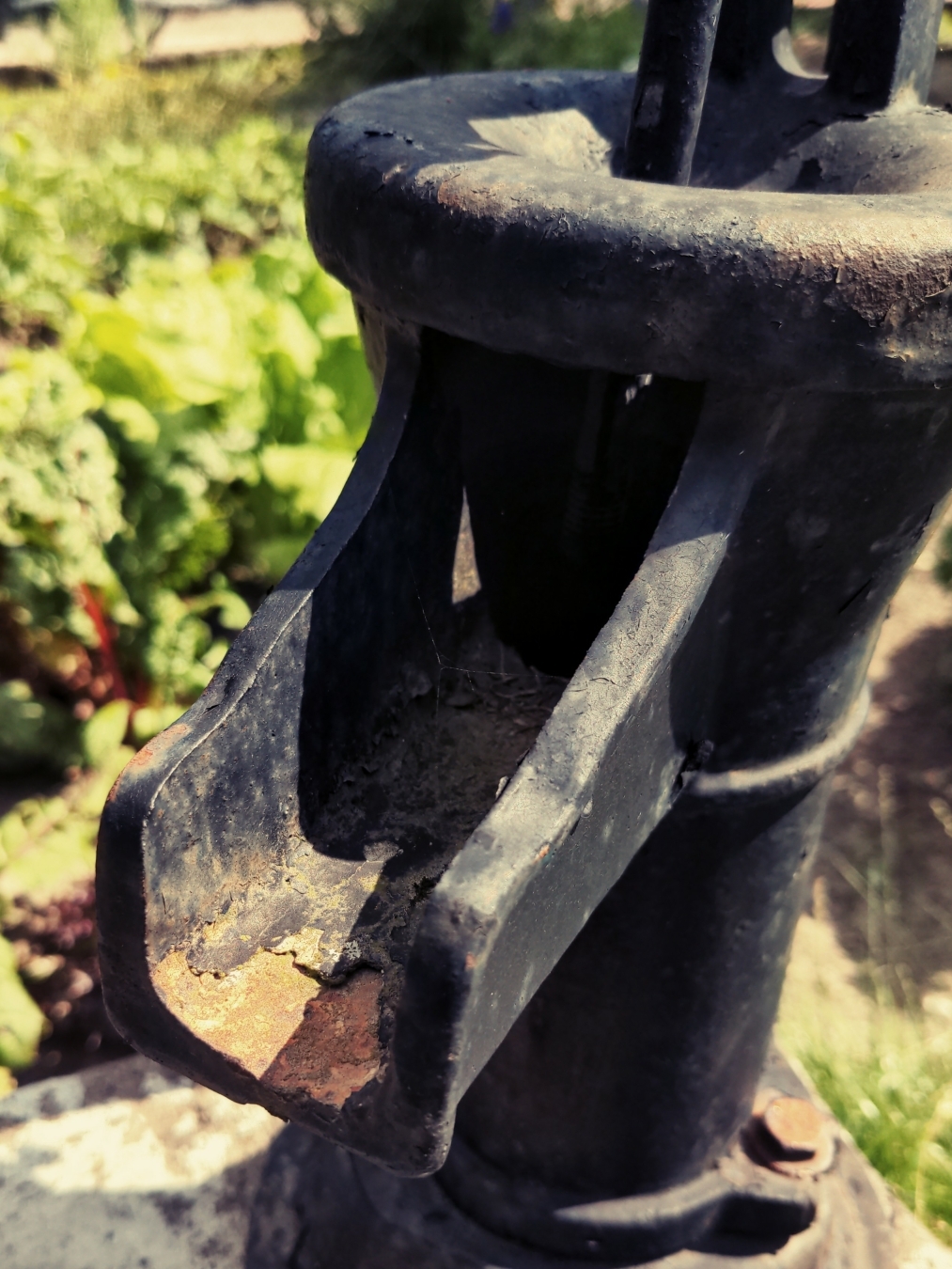 Eine verrostete Wasserpumpe in einem Garten.