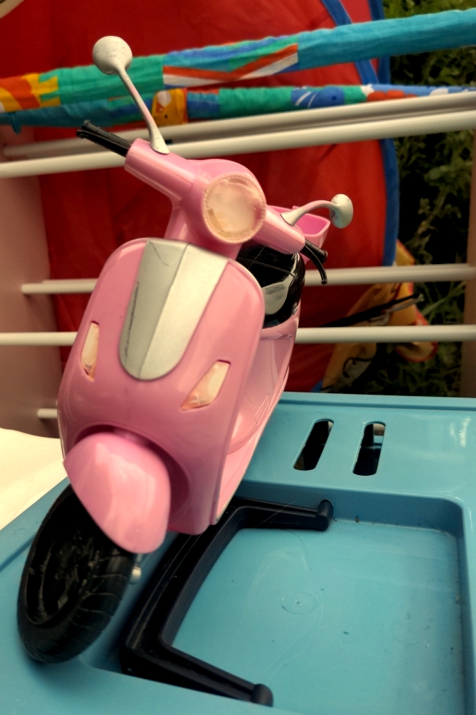 Ein rosa Spielzeugmotorroller, der im Sperrmüll steht.