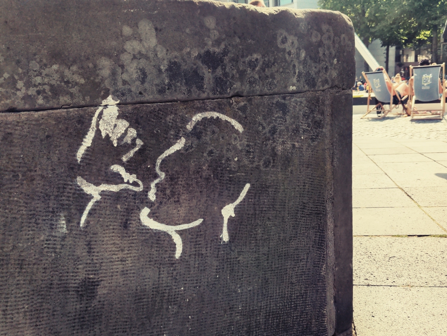 Ein Graffiti eines trinkenden Mannes auf einem Stein.